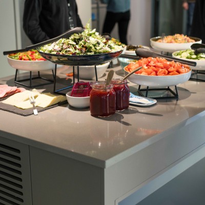 Et serveringsbord i en kantine som består av pålegg og grønnsaker.